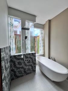 ein Badezimmer mit einer großen weißen Badewanne und einer Dusche in der Unterkunft The Inside House Medewi in Airsatang