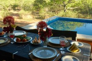 un tavolo con piatti di cibo su un tavolo con piscina di Zuri Camp - Tent Kiama a Tsumeb