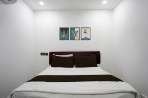 uma cama num quarto branco com duas fotografias na parede em Collection O Hingna City Court Nagpur Formerly Hotel Dream Inn em Khāpri mais 24 fotografias