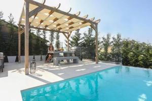 una donna seduta a un tavolo da picnic accanto a una piscina di Casa Grande Private Luxury Villa a Alykes Potamou