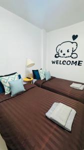 two beds in a bedroom with a welcome sign on the wall at Happy Home Samui near Mae Nam beach on main road in Ban Mae Nam