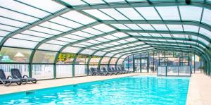 einen Innenpool mit Stühlen und einer Glasdecke in der Unterkunft Kabana Village in Saint-Hilaire-de-Riez