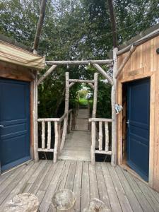 una passerella di legno con porte blu su un edificio di Chalet sur l'eau a Brissarthe Altre 5 foto