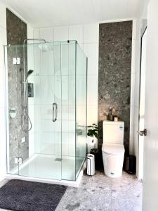 a bathroom with a glass shower with a toilet at Mangawhai Estuary Escape in Mangawhai