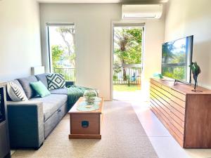 a living room with a couch and a tv at Mangawhai Estuary Escape in Mangawhai