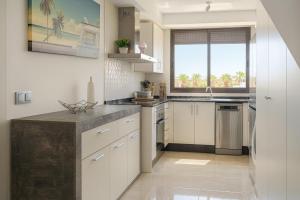 a kitchen with white cabinets and a large window at 3 bedroom, two-level, morden apartment in Orihuela Costa