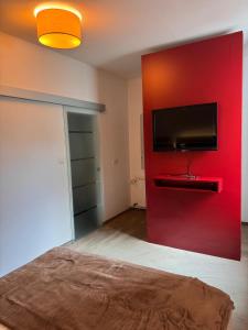a bedroom with a red wall with a flat screen tv at Hotel Restaurant Waldschlößchen in Neheim-Hüsten