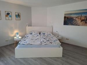 GaßFerienwohnung Kleine Auszeit im Hunsrück的一间白色卧室,配有一张床和两张桌子 更多2张照片