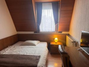 a bedroom with a bed and a desk and a window at Hotel Restaurant Waldschlößchen in Neheim-Hüsten