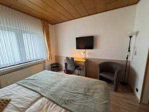 a bedroom with a bed and a desk and a television at Hotel Restaurant Waldschlößchen in Neheim-Hüsten +4 photos