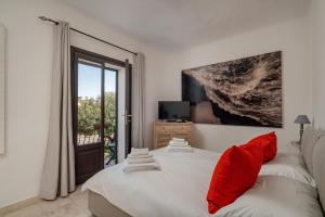 a bedroom with two beds with red pillows and a window at Estay - Locanda Tartarughino in Porto Rotondo
