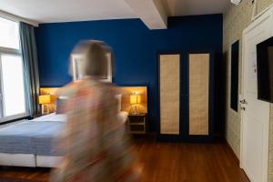 osoba w pokoju z łóżkiem i niebieskimi ścianami w obiekcie Boutique Hotel Malleberg w Brugii