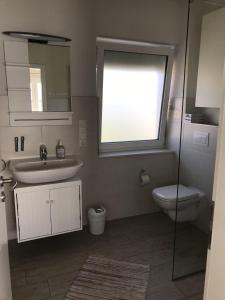 a bathroom with a sink and a toilet and a window at Strandhaus-Appartment-Rauchschwalbe in Fehmarnsund +12 photos
