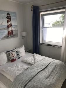 a bedroom with a bed and a window with a lighthouse at Strandhaus Appartement - Seeschwalbe OG in Fehmarnsund