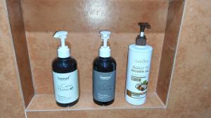 tre bottiglie di prodotti per capelli su uno scaffale di The Cat And The Kraken Paliton Jacuzzi Suites with Solar and Starlink a Siquijor