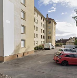 een rode auto geparkeerd op een parkeerplaats naast een gebouw bij le be good in Chalon-sur-Saône