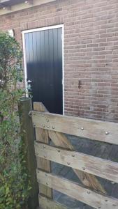 KeentGrazelands - overnachten midden in de natuur的砖墙前的木凳，墙边有一扇门