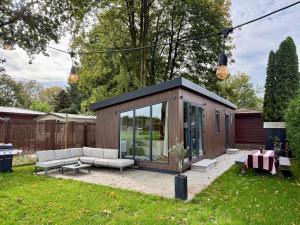 a small shed in a yard with a couch and a table at Tiny forest house met vrij uitzicht in Putten
