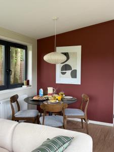 un soggiorno con tavolo, sedie e divano di Tiny forest house met vrij uitzicht a Putten