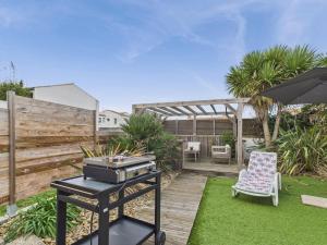 un barbecue in giardino con una sedia e un ombrellone di 400m de la mer - grande maison pour 10 avec jardin a La Tranche-sur-Mer