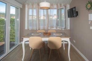 a dining room table and chairs in a room with windows at Porta da Seca casa con jardín y asador Rías Baixas in Poio