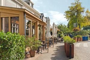 een restaurant met tafels en parasols op een stoep bij Abcoude city center in Abcoude