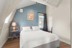 een slaapkamer met een wit bed en een blauwe muur bij Abcoude city center in Abcoude