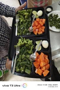 a table with two trays of food with forks and vegetables at Vilaasitaa Family Suites in Indore