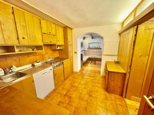 Cozy Apartment - Alverà في كورتينا دامبيتزو: مطبخ بدولاب خشبي ومغسلة ومكتب