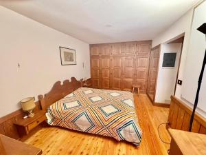 Cozy Apartment - Alverà في كورتينا دامبيتزو: غرفة نوم بسرير في غرفة ذات أرضيات خشبية