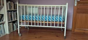 佩皮尼昂Agréable chambre d'hôte chez l'habitant的房间里，婴儿床就在书架旁边。