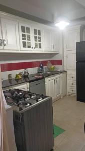 een keuken met witte kasten en een kookplaat oven bij Dortoir ily in Constantine