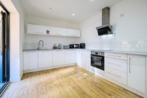 cocina con armarios blancos y suelo de madera en Modern 2 Bedroom Apartment, Free Parking, WiFi, en Gloucester