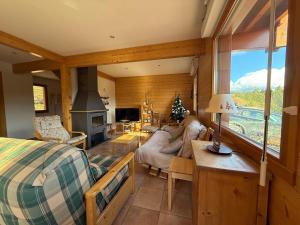 Le Chalet des Vanneaux في كسونبورت-لونجمير: غرفة نوم مع سرير وغرفة معيشة مع موقد