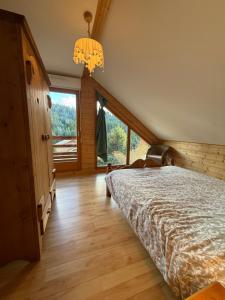 Le Chalet des Vanneaux في كسونبورت-لونجمير: غرفة نوم بها سرير ونافذة كبيرة