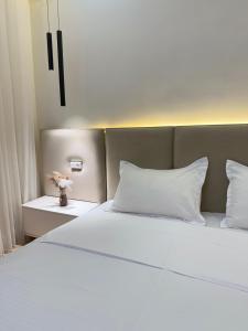 een bed met witte lakens en kussens in een kamer bij Altair in Simkent