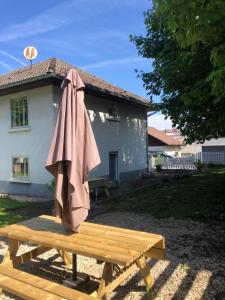 a brown umbrella sitting on a wooden bench in front of a house at Le repaire de l'horloger in Maîche
