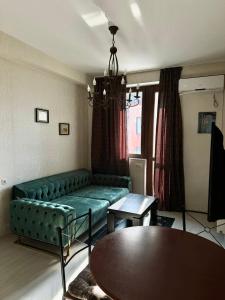 un soggiorno con un divano verde e un tavolo di Уютная и светлая квартира с видом на горы a Tbilisi City