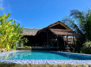 a resort with a swimming pool in front of a building at Lexias Hostel and Workspace - Siargao in Catagnan