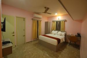 AG Corporate Stay in Mahindra World City في Singapperumālkovil: غرفة نوم بها سرير ومكتب وتلفزيون