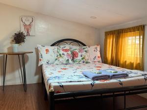 una camera da letto con un letto fiorito e una finestra di Green Glory Staycation in Amadeo a Cavite