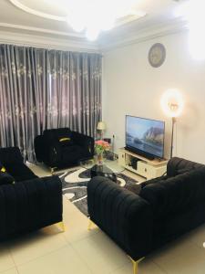 un soggiorno con mobili neri e TV a schermo piatto di MADO Appartement a Bonamoussadi