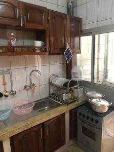 a kitchen with wooden cabinets and a sink and a stove at MADO Appartement in Bonamoussadi