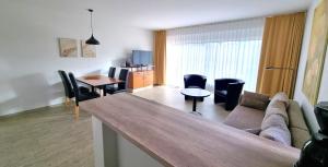 a living room with a couch and a table and chairs at Boddenhof Apartment 50 - modern und freundlich, viel Sonne in Buschvitz