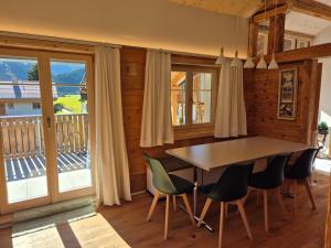 a dining room with a table and chairs and a balcony at Ferienwohnung Tgèsa Stefania in Sedrun