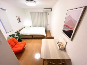 een slaapkamer met een bed, een tafel en een stoel bij Camelot House 南福岡 in Fukuoka