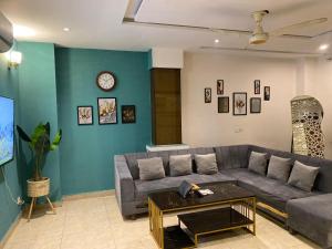 ein Wohnzimmer mit einer Couch und einer Uhr an der Wand in der Unterkunft 2 Bedroom Executive Suite in DHA Phase 8 in Lahore + 10 Fotos