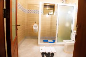 um banheiro com chuveiro, vaso sanitário e pia em DE ALena Villas And Hotel em Mbarara