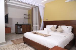 um quarto com uma grande cama branca e uma televisão em DE ALena Villas And Hotel em Mbarara