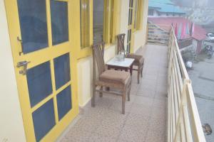 a porch with two chairs and a table on a balcony at Sahil cottage in Chamba